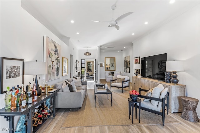 living room featuring ceiling fan, ornamental molding, and light hardwood / wood-style flooring