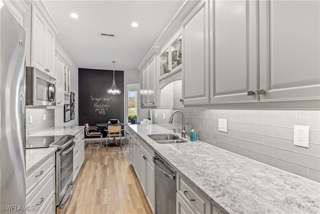 kitchen with stainless steel appliances, sink, decorative light fixtures, light hardwood / wood-style floors, and white cabinetry