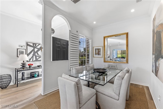 dining room with crown molding and light hardwood / wood-style flooring