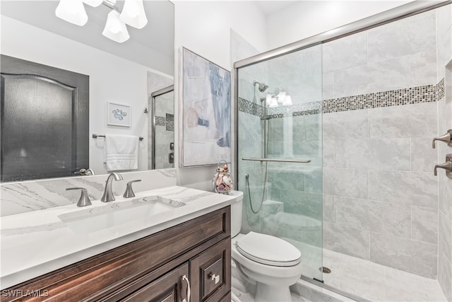 bathroom featuring toilet, an enclosed shower, and vanity