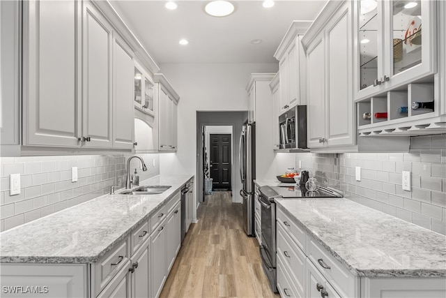 kitchen with sink, light wood-type flooring, light stone counters, white cabinetry, and stainless steel appliances