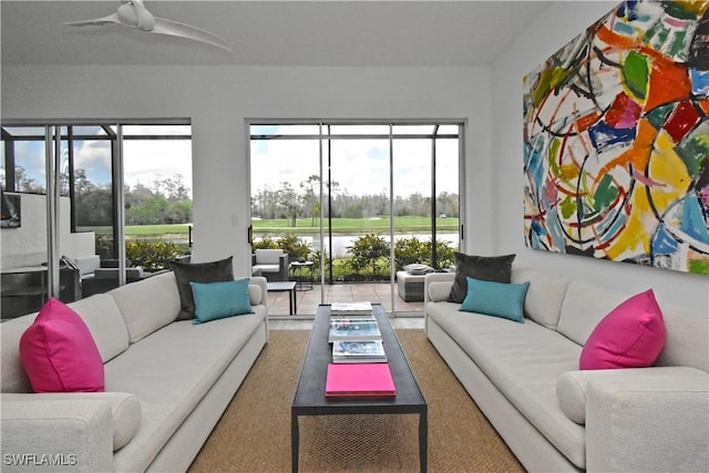 living area with ceiling fan and a water view