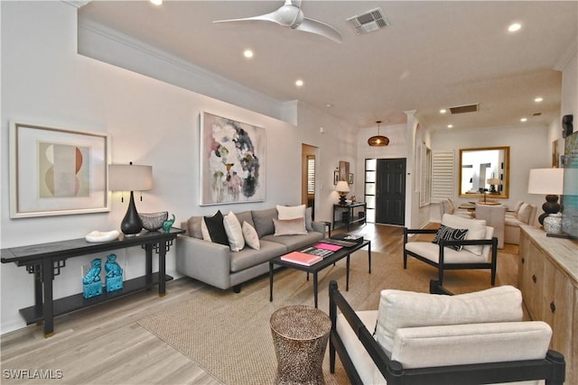 living room featuring crown molding, visible vents, and light wood-style floors