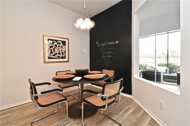 dining area featuring lofted ceiling, an inviting chandelier, baseboards, and wood finished floors