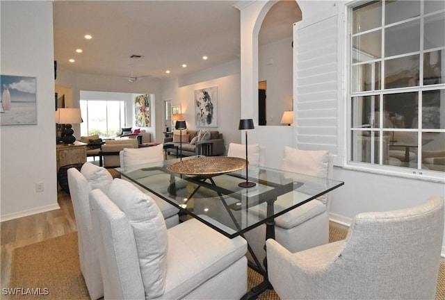 dining area featuring arched walkways, light wood-style flooring, recessed lighting, visible vents, and baseboards