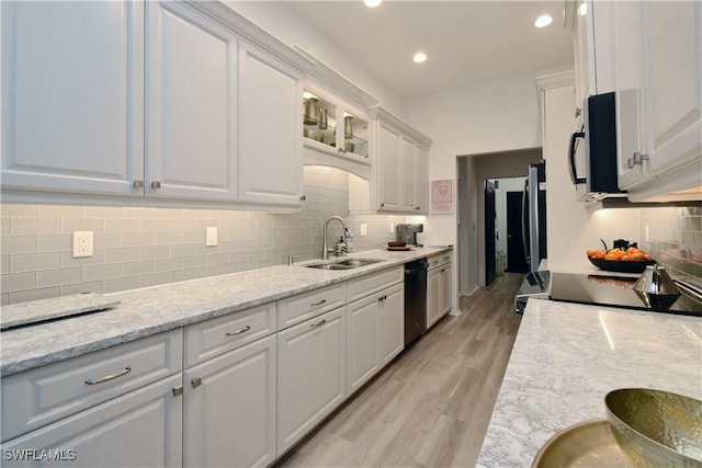 kitchen featuring white cabinets, glass insert cabinets, light stone countertops, black appliances, and a sink