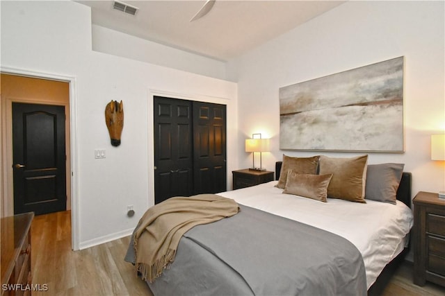 bedroom featuring a closet, visible vents, baseboards, and wood finished floors