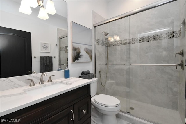 bathroom featuring toilet, a shower stall, and vanity