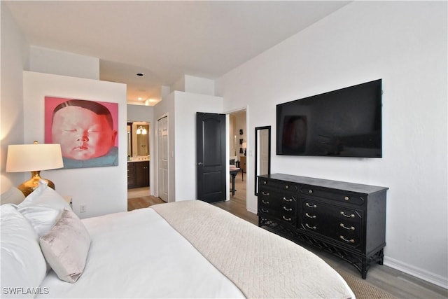 bedroom featuring ensuite bath, baseboards, and wood finished floors