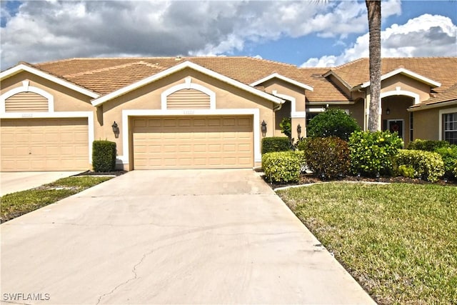 view of front of property with driveway, a front yard, an attached garage, and stucco siding