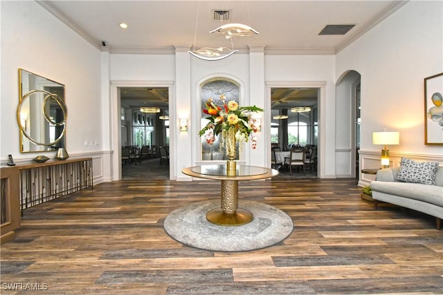 interior space with crown molding, arched walkways, wainscoting, and dark wood finished floors