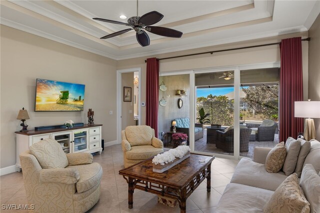 living room with crown molding, ceiling fan, a tray ceiling, and light tile patterned floors