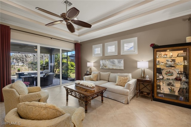 living room featuring light tile patterned floors, a tray ceiling, ornamental molding, and ceiling fan