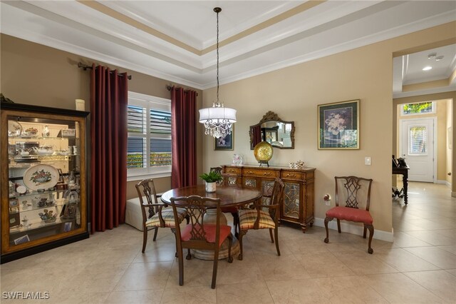 tiled dining area featuring a tray ceiling, ornamental molding, and a chandelier