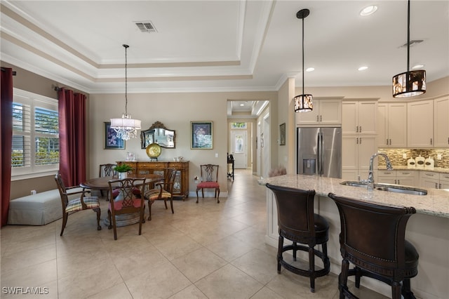 kitchen with light stone counters, sink, a raised ceiling, and stainless steel refrigerator with ice dispenser