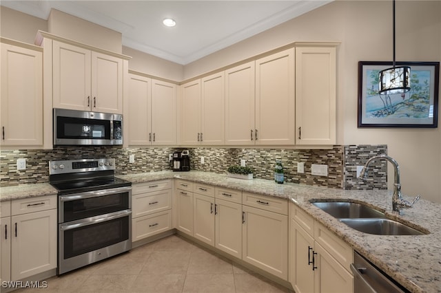 kitchen featuring sink, ornamental molding, appliances with stainless steel finishes, pendant lighting, and light stone countertops