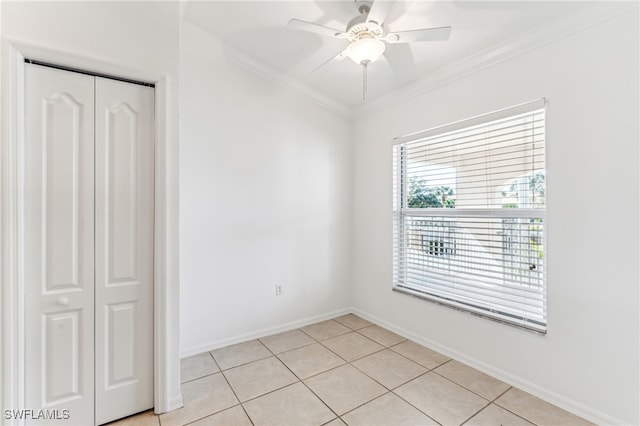 tiled empty room with ceiling fan and crown molding