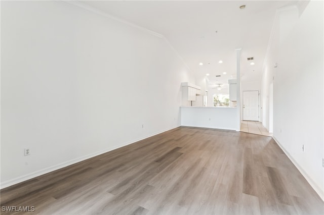 unfurnished living room featuring ceiling fan, light wood-type flooring, and ornamental molding