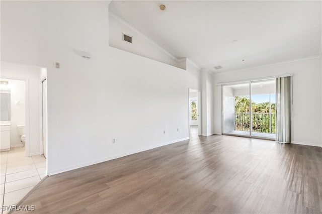 unfurnished room featuring light hardwood / wood-style floors, crown molding, and high vaulted ceiling