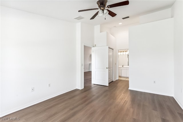 unfurnished bedroom with ceiling fan, dark hardwood / wood-style floors, a high ceiling, and connected bathroom