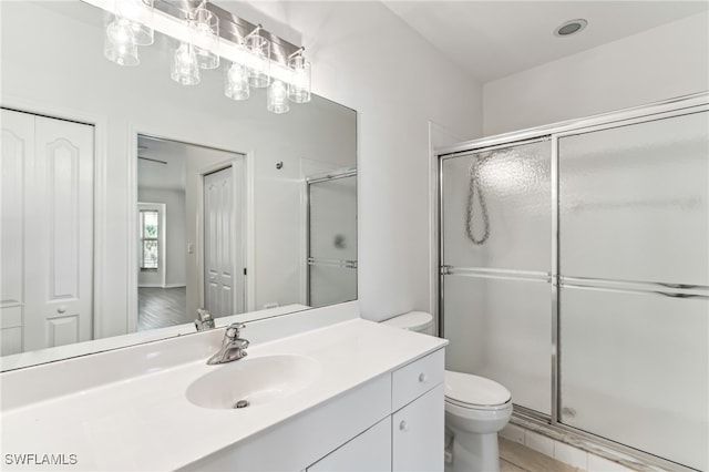 bathroom with vanity, a shower with shower door, and toilet