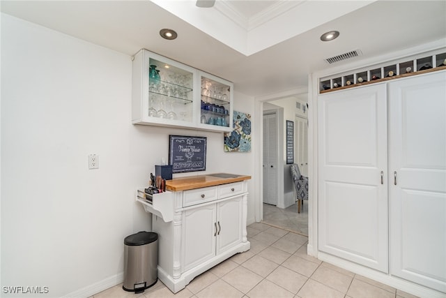 kitchen featuring butcher block counters, white cabinetry, light tile patterned flooring, and ornamental molding