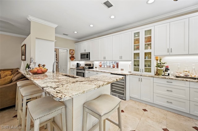 kitchen with stainless steel appliances, white cabinetry, beverage cooler, and a kitchen breakfast bar