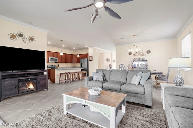 living room featuring ceiling fan with notable chandelier, sink, light tile patterned floors, and crown molding