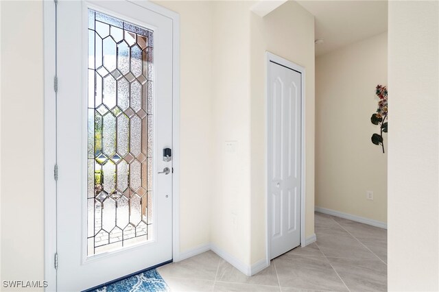 foyer featuring light tile patterned flooring and baseboards