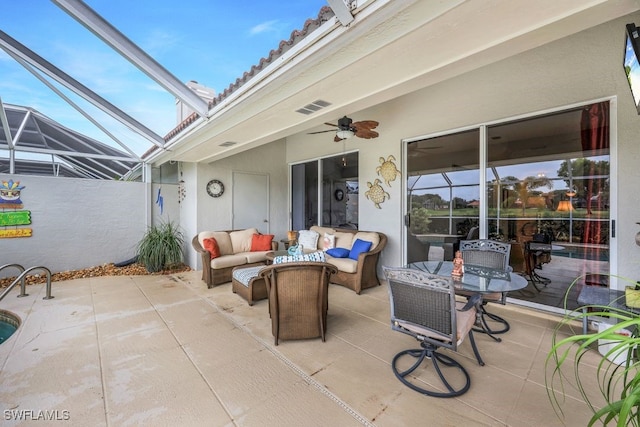 view of patio featuring an outdoor living space, ceiling fan, and glass enclosure