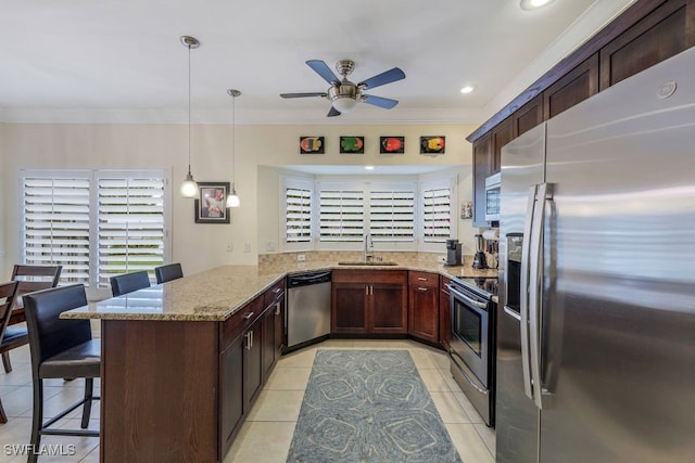 kitchen featuring pendant lighting, a kitchen breakfast bar, appliances with stainless steel finishes, light stone counters, and kitchen peninsula