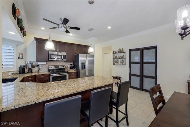 kitchen featuring light stone countertops, hanging light fixtures, kitchen peninsula, light tile patterned floors, and appliances with stainless steel finishes