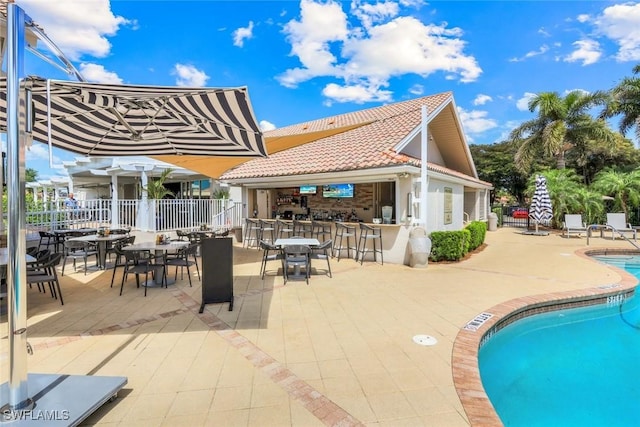 community pool featuring outdoor dry bar, fence, and a patio