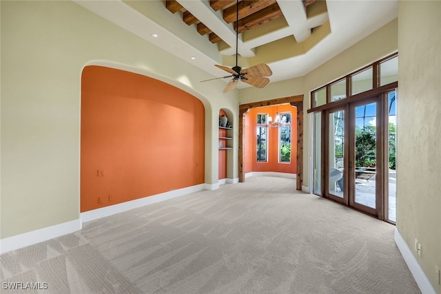 carpeted empty room with ceiling fan, beam ceiling, a towering ceiling, and coffered ceiling