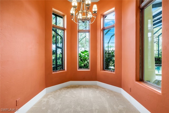 carpeted spare room featuring a chandelier