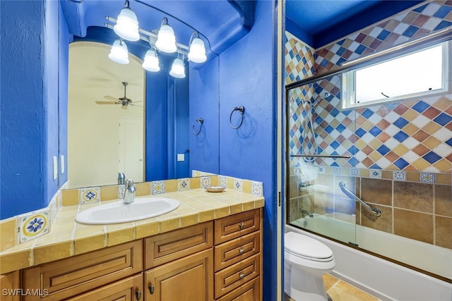 full bathroom with ceiling fan, tile patterned flooring, bath / shower combo with glass door, toilet, and vanity