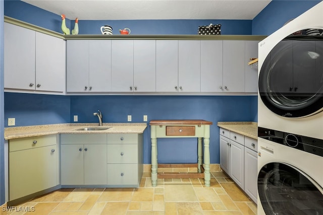 clothes washing area featuring stacked washer / drying machine, cabinets, and sink