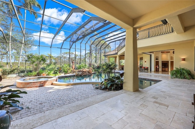 view of pool featuring glass enclosure, an in ground hot tub, a fireplace, and a patio area