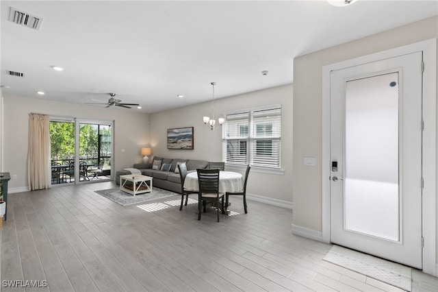 dining room with ceiling fan with notable chandelier and light wood-type flooring