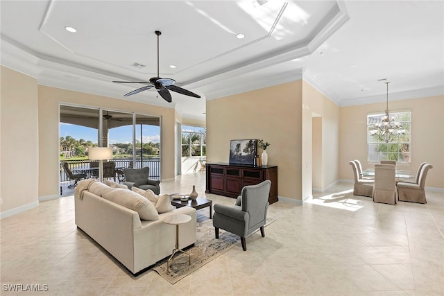 living room featuring a raised ceiling, plenty of natural light, ceiling fan with notable chandelier, and ornamental molding