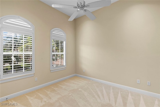 carpeted spare room featuring a wealth of natural light and ceiling fan