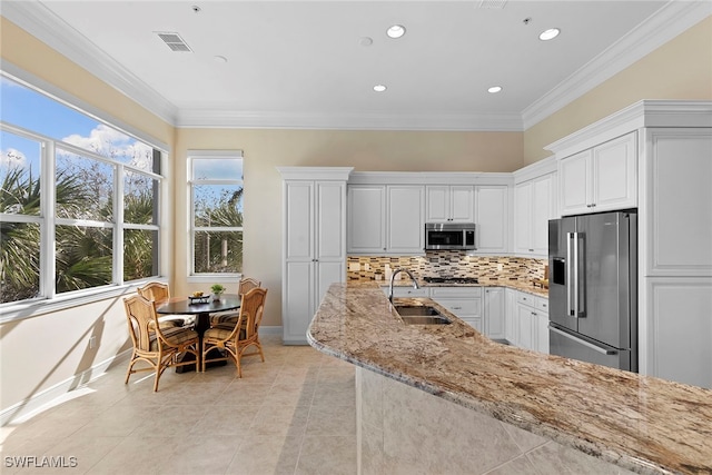 kitchen with white cabinets, appliances with stainless steel finishes, light stone countertops, and sink