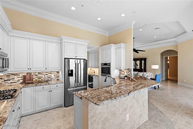 kitchen featuring white cabinetry, light stone countertops, tasteful backsplash, crown molding, and appliances with stainless steel finishes