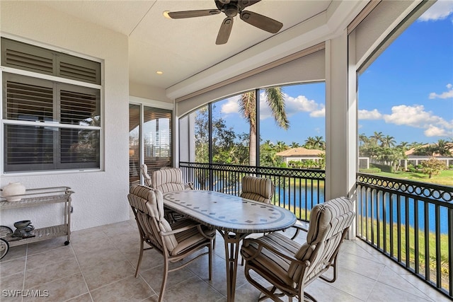 sunroom featuring ceiling fan and a water view