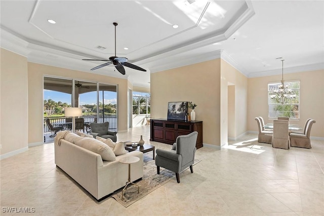 living room featuring a wealth of natural light, ceiling fan with notable chandelier, a tray ceiling, and ornamental molding