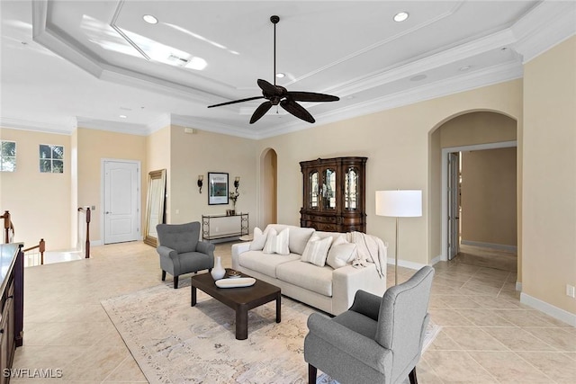 living room with baseboards, ornamental molding, light tile patterned floors, arched walkways, and a raised ceiling