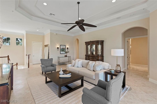 living room with visible vents, ceiling fan, a tray ceiling, ornamental molding, and arched walkways