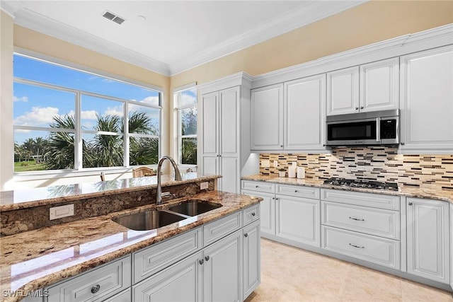 kitchen featuring tasteful backsplash, visible vents, crown molding, stainless steel appliances, and a sink