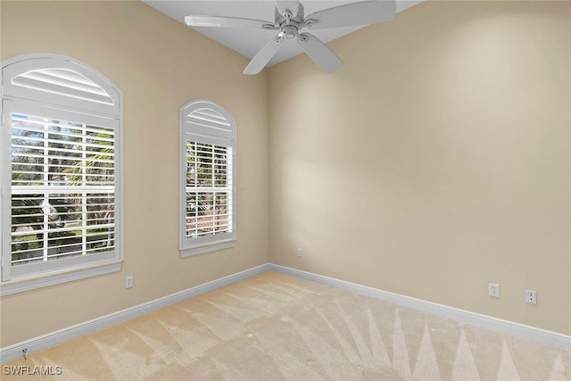 carpeted spare room featuring a ceiling fan and baseboards