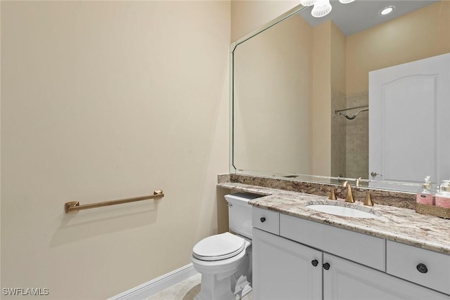 bathroom featuring vanity, toilet, a shower, and baseboards